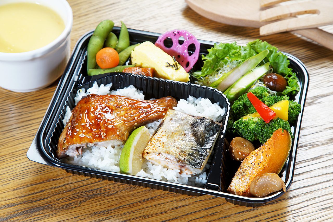 分格會議餐盒，盛裝烤雞腿排、魚排、白飯與時蔬，旁邊附一碗濃湯