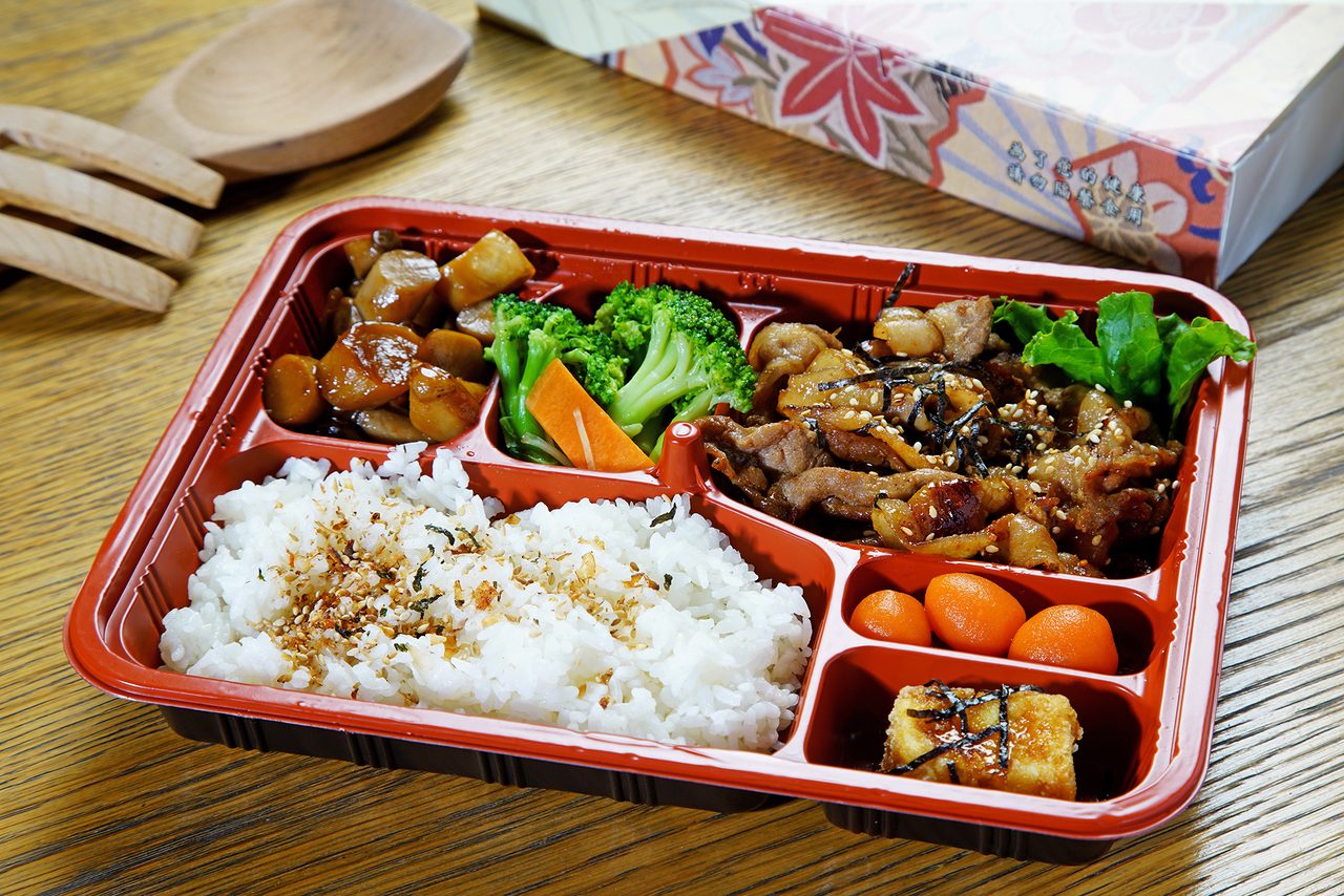 紅黑雙色會議餐盒，白飯搭配燒肉、花椰菜、紅蘿蔔與滷蛋，分格盛裝
