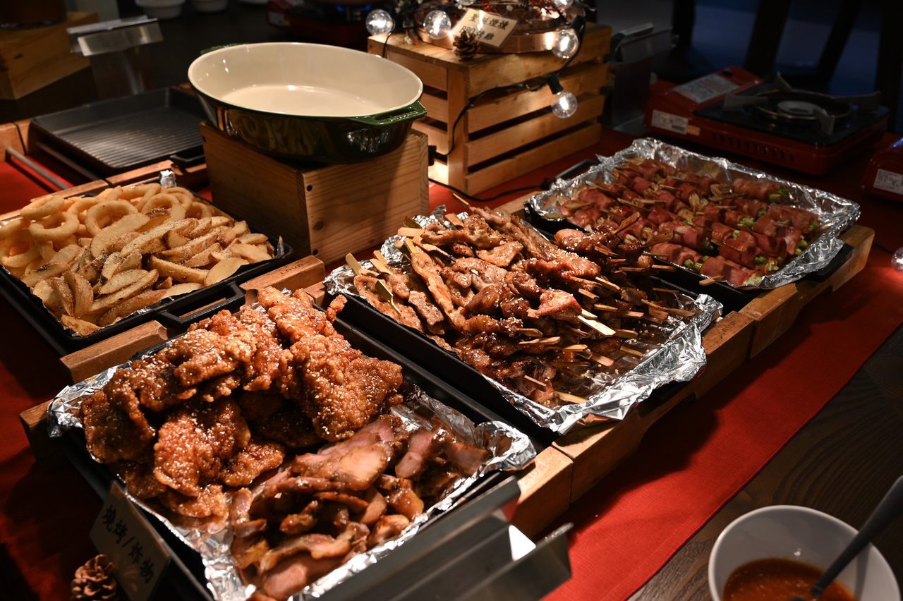 燒烤區的錫箔烤盤裡盛滿烤肉與炸物，旁邊備有醬料鍋，供現場大量供餐